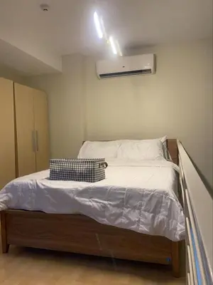a small bedroom with a bed with white sheets at The Gramercy Residences Unit for Rent in Manila