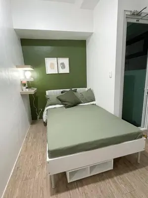 a bed in a room with a green wall at Cozy aesthetic stay near Alabang in Manila