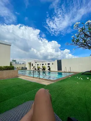 a person laying on the grass next to a swimming pool at Elevated Staycation BGC Venice Grand Canal in Manila