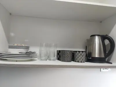 a shelf with plates and a coffee pot and glasses at 2br Condo Coast Residence near MOA NAIA Ayala WTC in Manila
