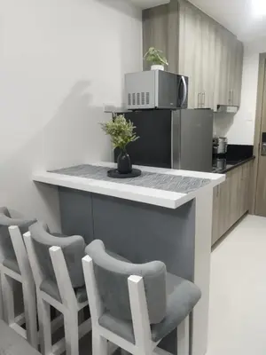 a kitchen with a counter with chairs and a microwave at 2br Condo Coast Residence near MOA NAIA Ayala WTC in Manila