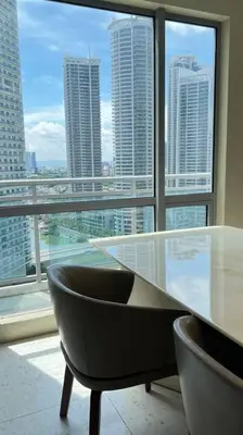 a glass table and chairs in front of a large window at Staycation at ACQUA The Hotel Residences Novotel Tower in Manila