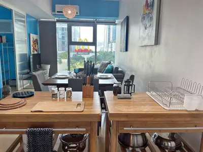 a kitchen with wooden tables and a living room at Marina- Avant BGC parking w fee in Manila
