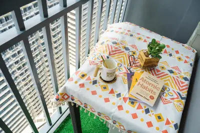 a table with a cup of coffee and a book on a balcony at Nordic Place Fame Residences 75 Smart Amenities Alexa 200mbps Wifi Netflix in Manila