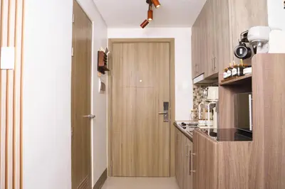 a kitchen with wooden cabinets and a door at Nordic Place Fame Residences 75 Smart Amenities Alexa 200mbps Wifi Netflix in Manila