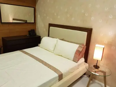 a bedroom with a bed and a table with a lamp at Twin Oaks Place West Tower in Manila
