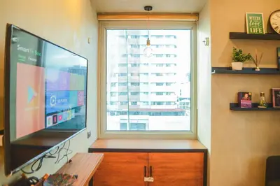 a living room with a large television and a window at Stylish 1BR Near US Embassy & Luneta with Pool & Gym in Manila