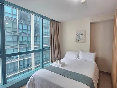 a bedroom with a bed and a large window at One Uptown Executive 2 bedroom, with balcony, washer & Netflix in Manila