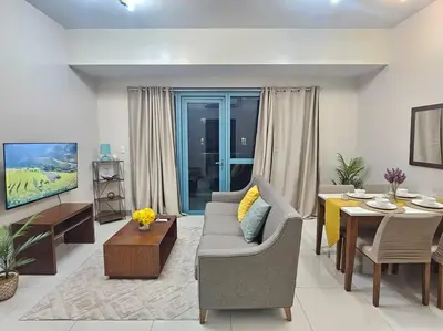 a living room with a couch and a table at One Uptown Executive 2 bedroom, with balcony, washer & Netflix in Manila