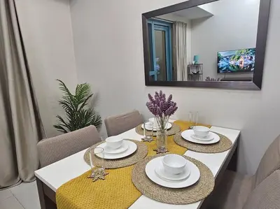 a dining room table with two plates and a mirror at One Uptown Executive 2 bedroom, with balcony, washer & Netflix in Manila