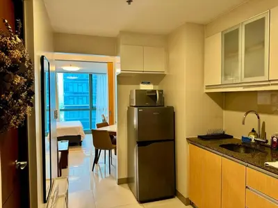 a kitchen with a stainless steel refrigerator and a table at BGC 1BR unit linked to Uptown Mall with own parking in Manila