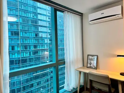 a room with a desk and a large window at BGC 1BR unit linked to Uptown Mall with own parking in Manila