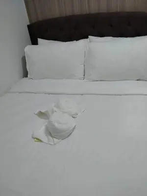 a white bed with a hat and towels on it at Comfy 19 shore2 Residence Free parking, Near Airport, IKEA, MOA, Pasay City in Manila
