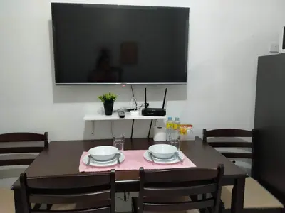 a dining room table with a tv on the wall at Comfy 22 shore2 Residence Free parking, Near Airport, IKEA, MOA, Pasay City in Manila
