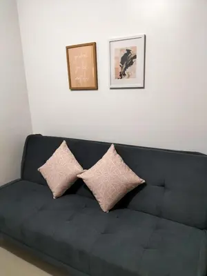 a black couch with two pillows against a white wall at Comfy 22 shore2 Residence Free parking, Near Airport, IKEA, MOA, Pasay City in Manila