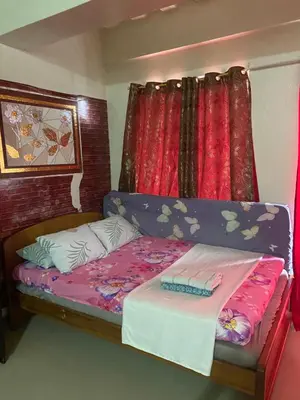 a bed in a room with a red curtain at Hungary109 Service Apartments Near Airport at Kassel Residences in Manila