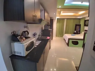 a kitchen with a microwave and a bed in a room at Executive Studio Apartment in BGC in Manila
