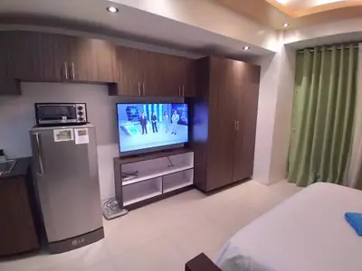 a living room with a flat screen tv in a room at Executive Studio Apartment in BGC in Manila