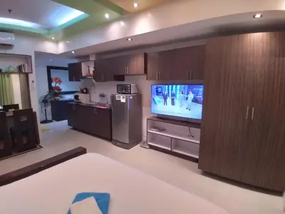 a living room with a television and a kitchen at Executive Studio Apartment in BGC in Manila