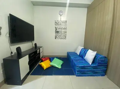 a living room with a couch and a flat screen tv at Shore2 Condo 1BR Balcony, Wifi, Pool, MOA, Airport in Manila