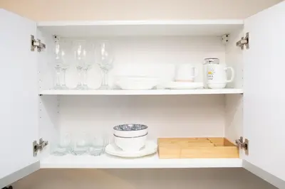 a cupboard filled with glasses and plates and bowls at Modern Living 3 Makati in Manila