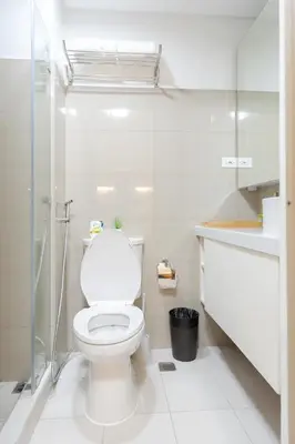 a white bathroom with a toilet and a glass shower at Modern Living 4 MOA Pasay in Manila