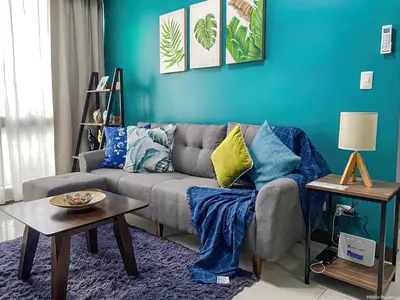 a living room with a couch and a blue wall at BGC McKinley Taguig 1BR with Balcony near Venice Grand Canal mall in Manila
