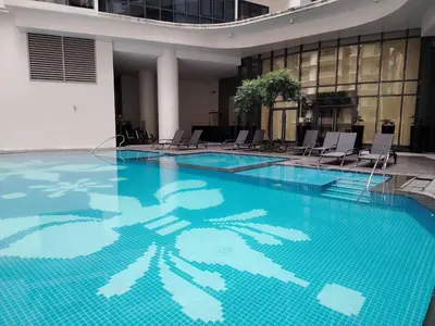 a large swimming pool with chairs in a building at BGC McKinley Taguig 1BR with Balcony near Venice Grand Canal mall in Manila