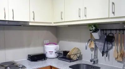 a kitchen counter with a sink and white cabinets at BGC McKinley Taguig 1BR with Balcony near Venice Grand Canal mall in Manila