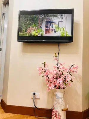 a tv hanging on a wall with flowers in a vase at Cozy apartment near Greenbelt Makati City in Manila