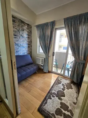 a living room with a blue couch and a large window at Cozy apartment near Greenbelt Makati City in Manila