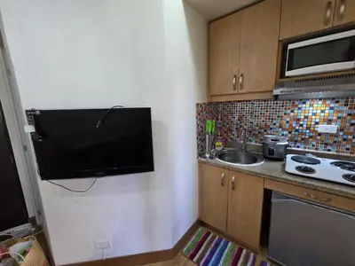 a small kitchen with a sink and a tv on the wall at Cozy apartment near Greenbelt Makati City in Manila