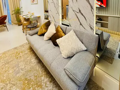 a gray couch with pillows in a living room at The Luxe Haven Shore 3 Residences in Manila