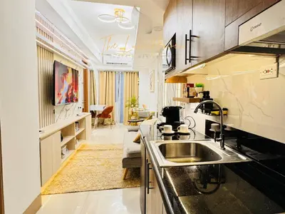 a kitchen with a sink and a living room at The Luxe Haven Shore 3 Residences in Manila