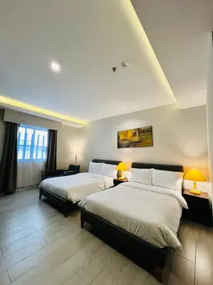 two beds in a hotel room with two lamps at Centennial Inn in Kawit