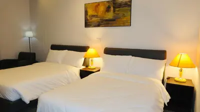 two beds in a hotel room with two lamps at Centennial Inn in Kawit