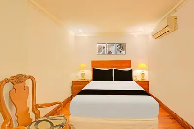 a bedroom with a bed and two lamps and a chair at Townhouse OAK Makati Manila Near PNR Pasay Evangelista formerly VIP Suites in Manila