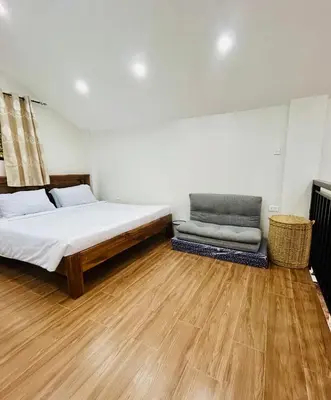 a bedroom with a bed and a chair in it at Tagaytay's Cozy Loft-type Forest House and Camp in Silang