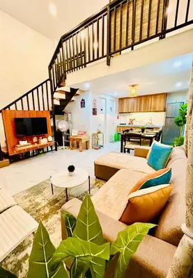 a living room with a couch and some plants at Tagaytay's Cozy Loft-type Forest House and Camp in Silang