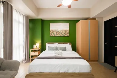 a bedroom with a green wall with a bed at Ocuna Suite - NAIA Manila Airport in Manila