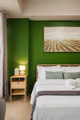 a green bedroom with a bed and a night stand with a table at Ocuna Suite - NAIA Manila Airport in Manila