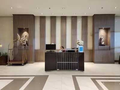 a woman sitting at a desk in a lobby at Ocuna Suite - NAIA Manila Airport in Manila