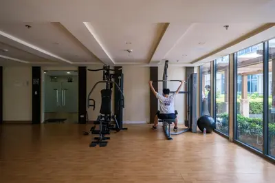 a man exercising in a gym with weights at Ocuna Suite - NAIA Manila Airport in Manila