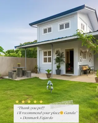 a white house with a sign in a yard at Tinyhaven Transient Cabuyao in Cabuyao