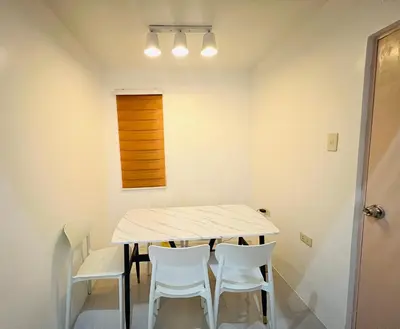 a dining room with a table and white chairs at Tinyhaven Transient Cabuyao in Cabuyao