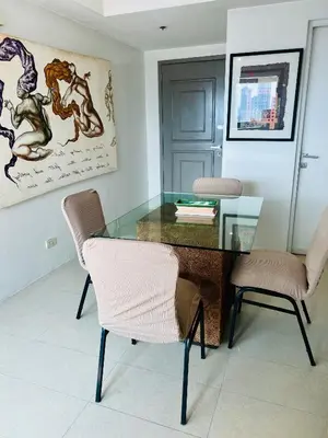 a glass table and two chairs in a room at Spacious 1BR steps to Megamall Ortigas City View in Manila