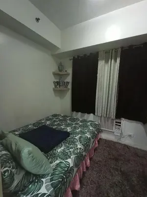 a bedroom with a bed with a green comforter and a window at Sea Residences Staycation Near Moa Pasay by Jhay in Manila