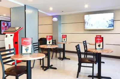 a restaurant with four tables and chairs and a screen at Hotel Sogo - Pasay Rotonda in Manila