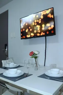 a table with plates and glasses and a tv on the wall at Condo Studio Luxe in Princeton Residences in Manila