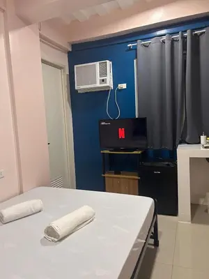 a room with a bed and a air conditioner on a blue wall at Origin Studios - Walk to Highstreet, BGC in Manila